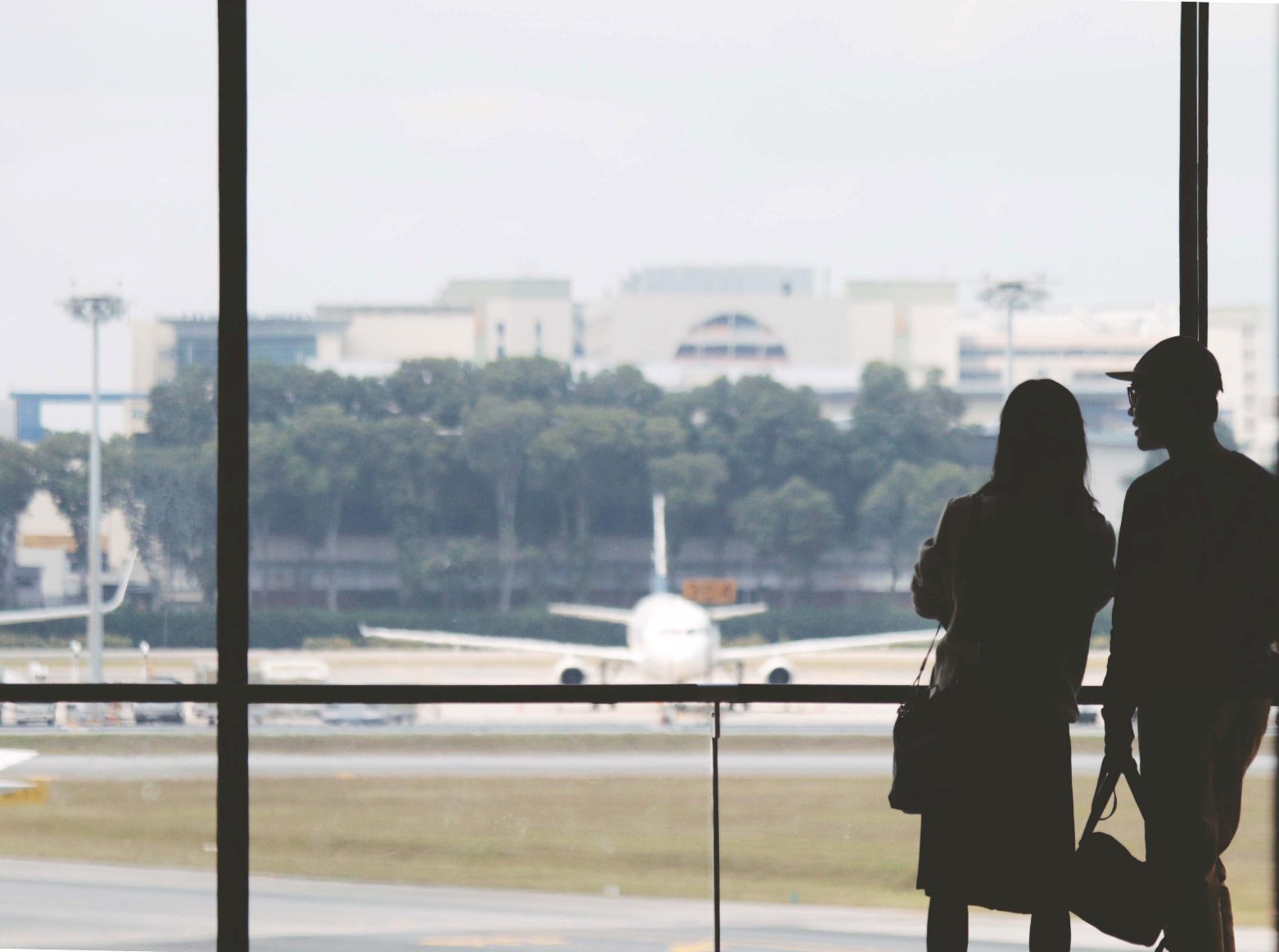 A couple standing in front of a window at the airport